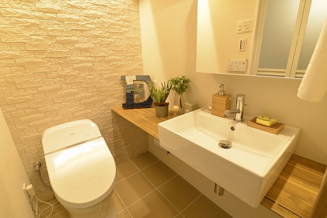 タンクレストイレとシンプルな洗面台のあるドレッシングルーム。壁面は除湿・脱臭効果のあるタイルを採用。