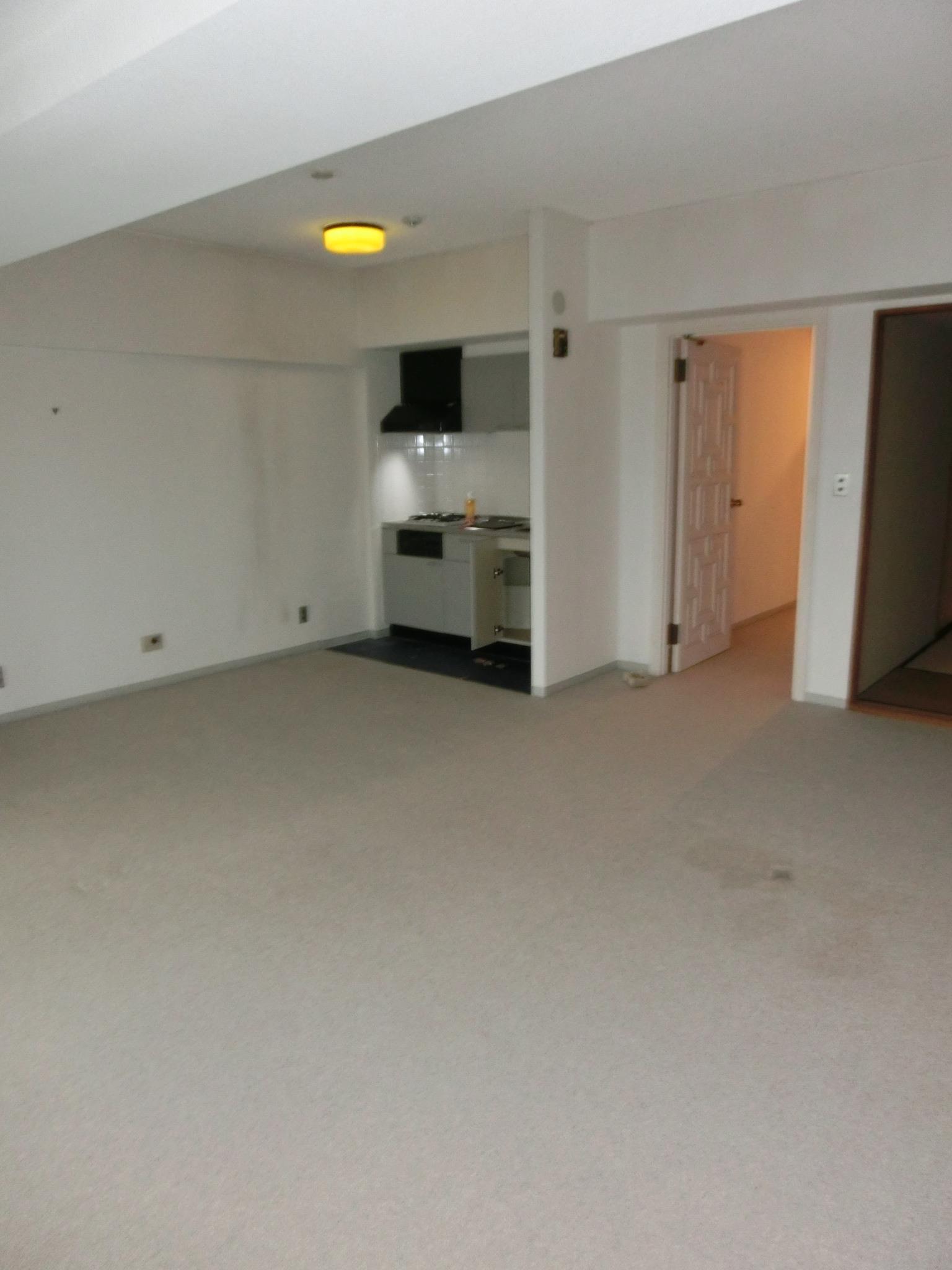 【Before】　リノベーション前のマンションのLDKには絨毯が敷かれ、ミニキッチンが設置されていました。
